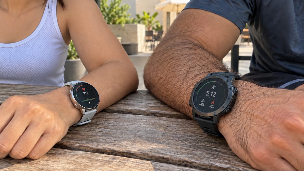 Two GPS sports watches in different sizes worn by a woman and a man at a table